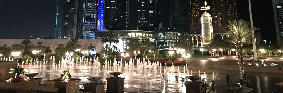 Nächtlicher Blick auf den beleuchteten Brunnen vor dem Emirates Palace Hotel und die Jumeirah at Etihad Towers in Abu Dhabi.